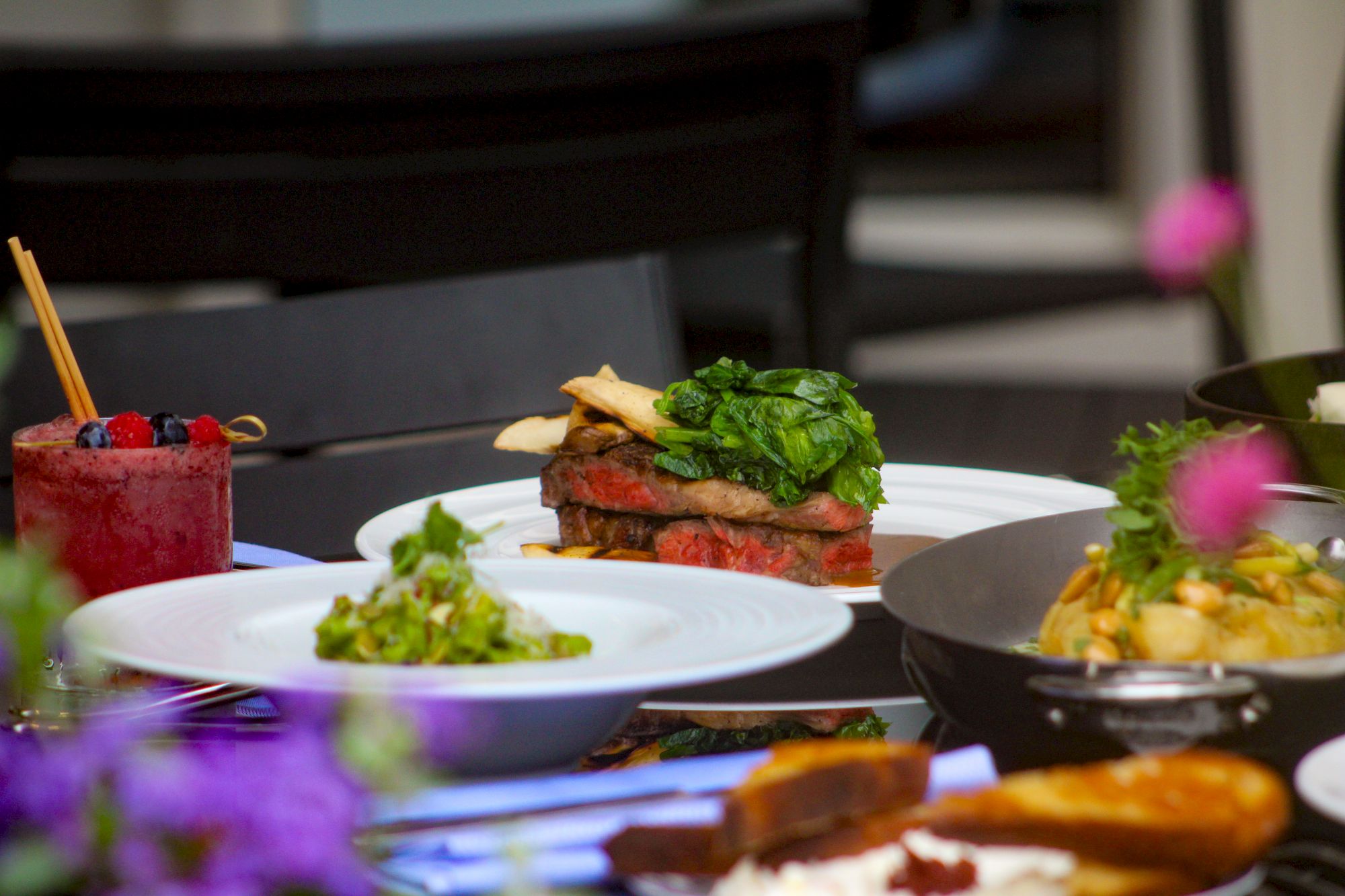 A variety of colorful dishes on a table, including a layered vegetable dish, a dessert with berries, and garnished appetizer plates.
